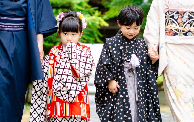 七五三で着飾った女の子と男の子が、それぞれパパとママに手を引かれている