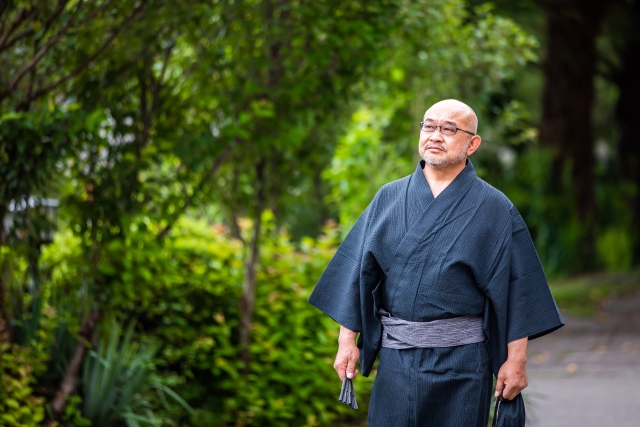 ねずみ色の着物を着た、恰幅のいい日本の中年男性