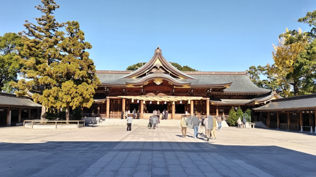 青空の下、寒川神社の本殿を正面から望む。左手には二本のご神木が見える。