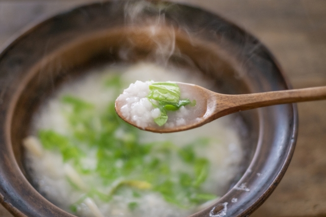 椀に入れられた七草がゆを、さじですくっている。湯気がたっておいしそう。